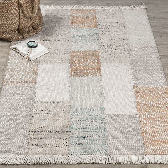 Ritsa rug close-up of patchwork squares in beige and cream with white fringe along border