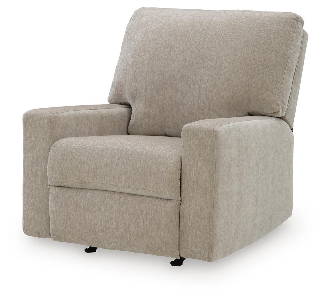 Beige fabric rocker recliner with wide seat, padded backrest, and side arms.