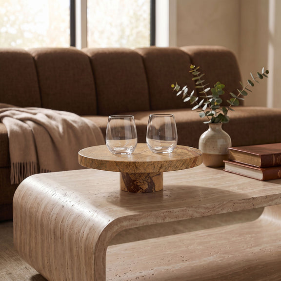 Beige marble pedestal serving tray with round top, displayed on a wooden table