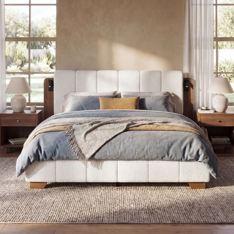 White upholstered platform bed with cushioned headboard, pillows, and side reading lights