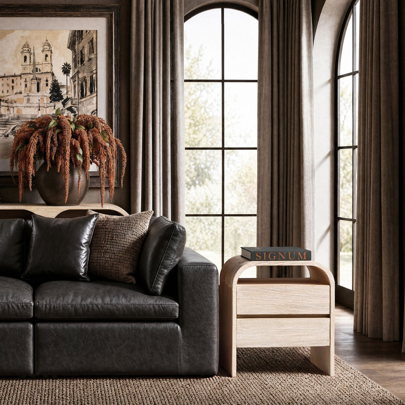 White-washed wood side table with two drawers beside a sofa