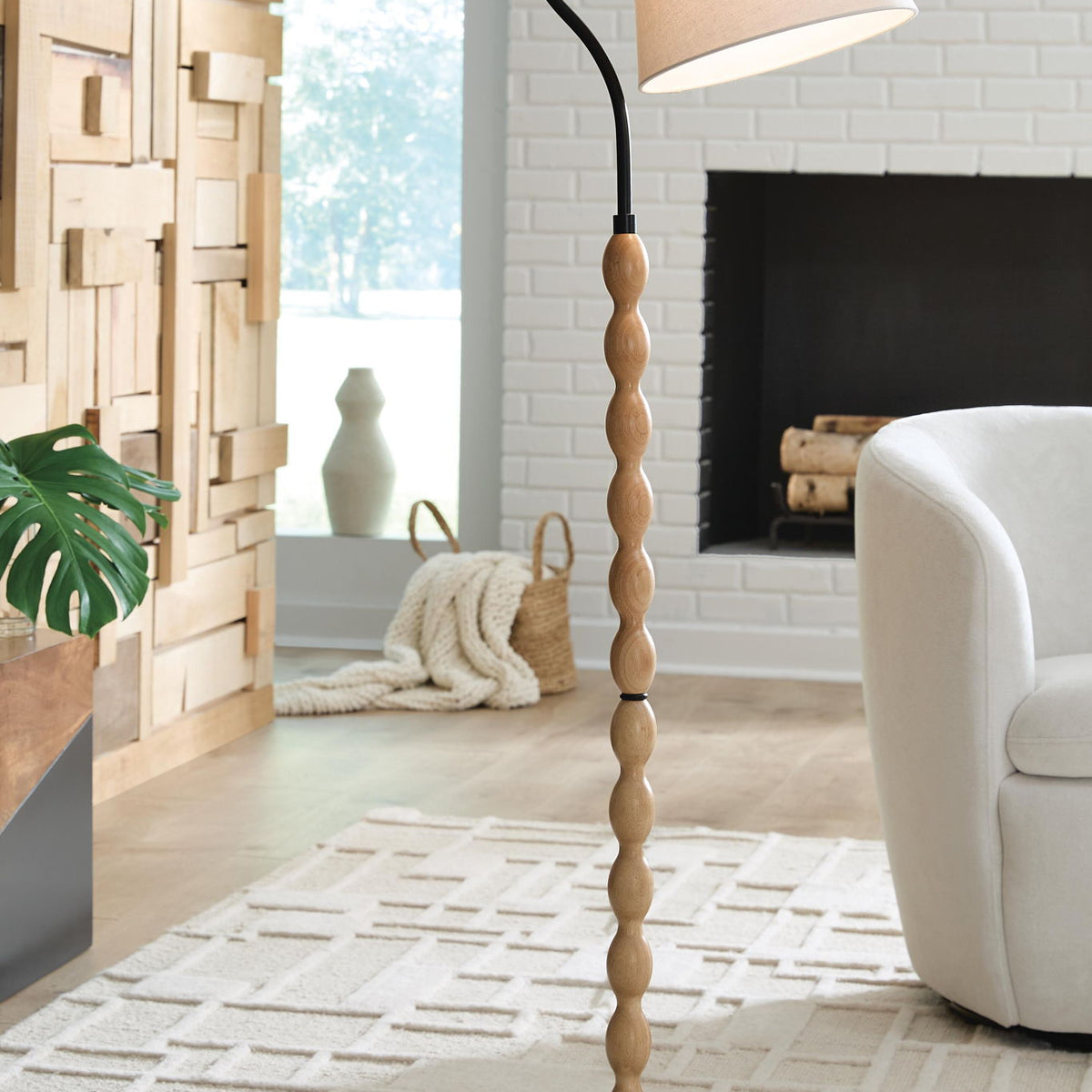 Brown wood floor lamp with black curved stand, beige drum shade, round base