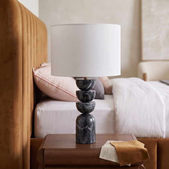 Table lamp on side table with tan fabric drum shade and stacked dark marble base