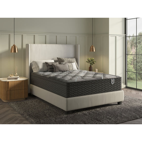 Dark gray queen hybrid plush mattress with white sheets and pillows on bed