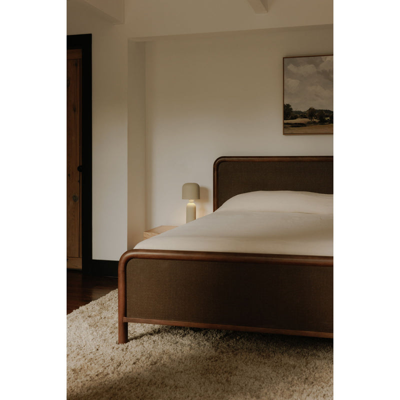Queen bed with warm brown wood posts and dark brown upholstered headboard