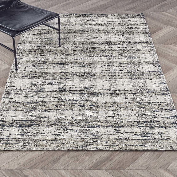 Textured abstract area rug, ivory with speckled blue lines, laid flat