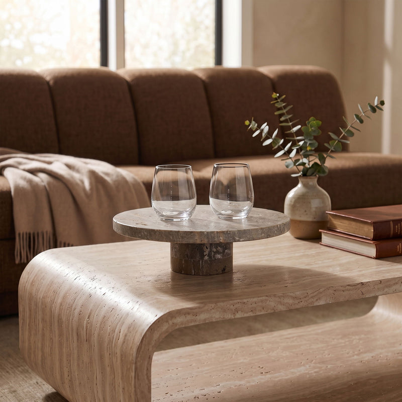 Round travertine tray on pedestal with two clear glasses and small vase