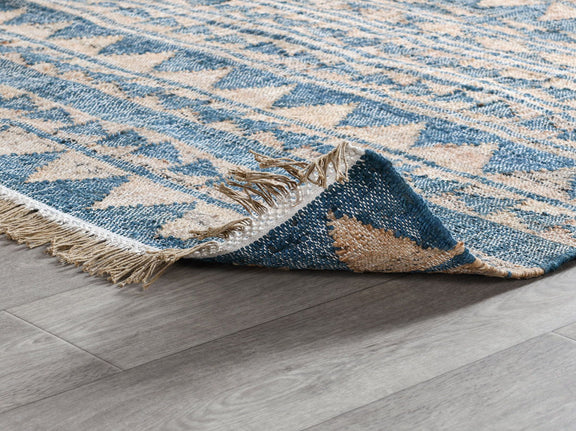 Solana rug in distressed blue and natural with geometric motif and fringed corner.