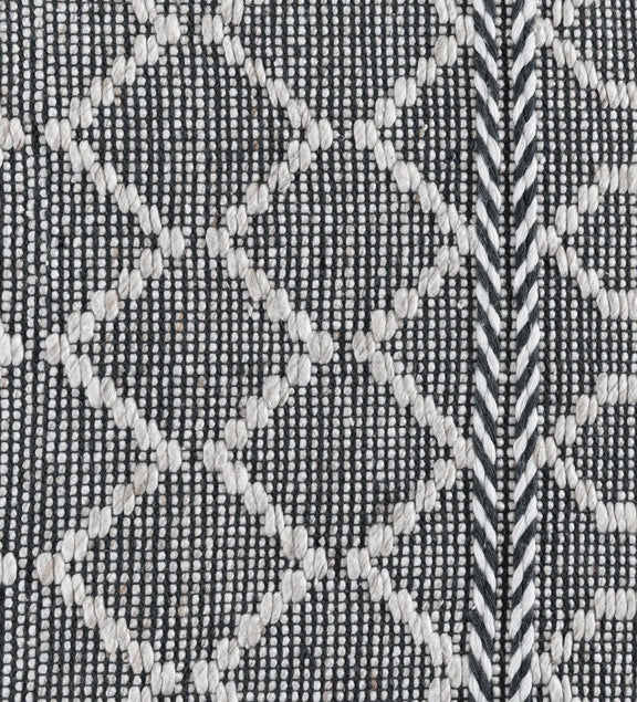 Close-up of black indoor/outdoor rug with white diamond shapes and dotted texture