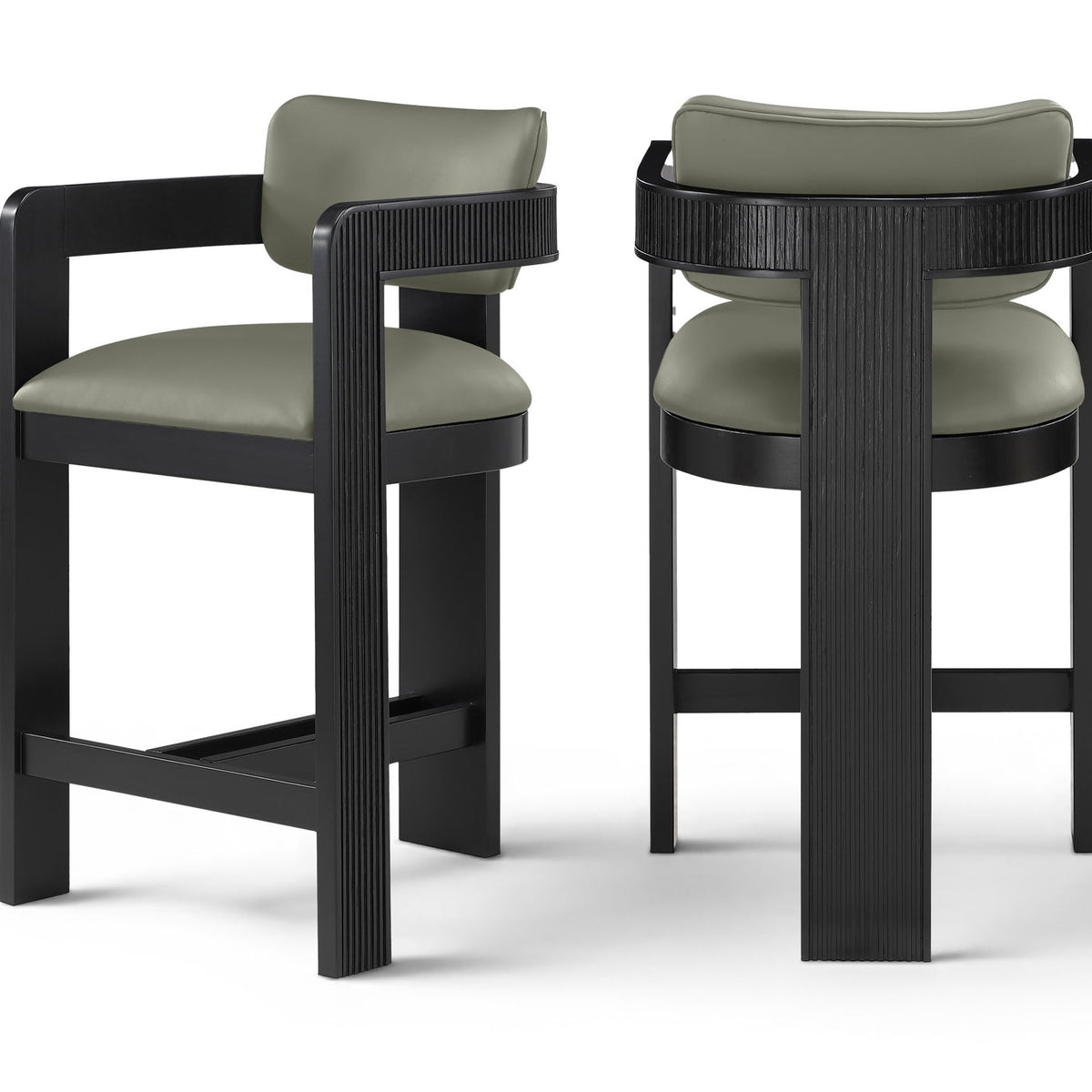 Two vegan leather counter stools with light green upholstered seats and black ribbed frames
