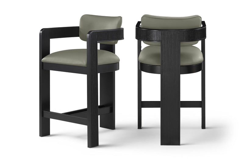 Two vegan leather counter stools with light green upholstered seats and black ribbed frames