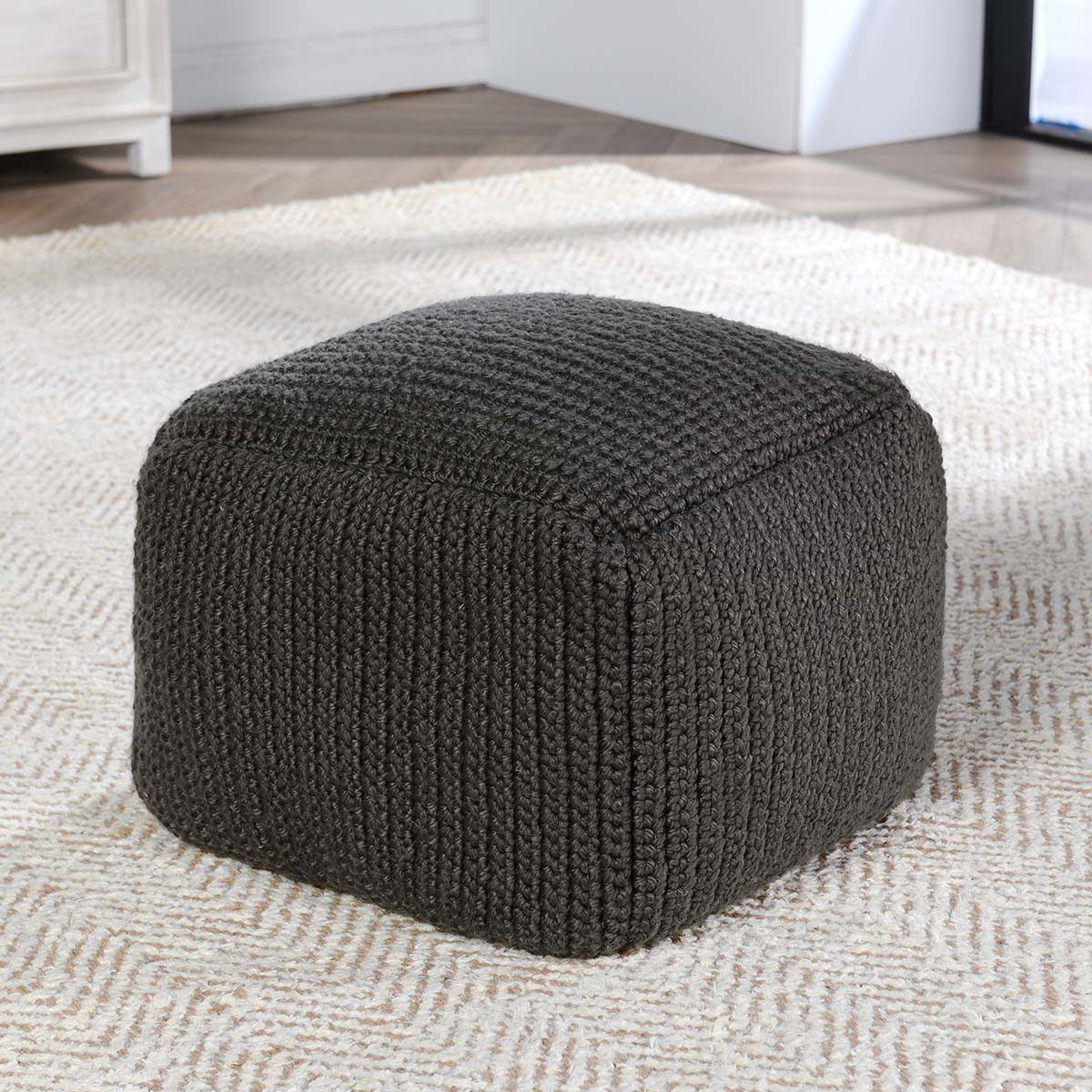 Dark gray knitted pouf with ribbed texture and squared rounded sides