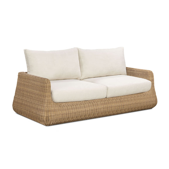 Outdoor sofa with white seat and back cushions on brown woven wicker