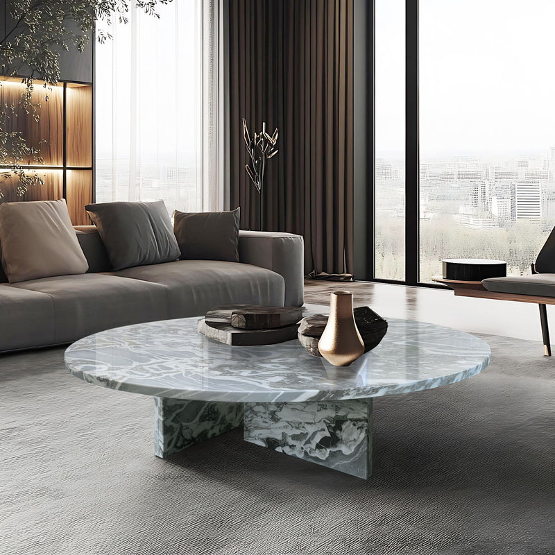 Round marble coffee table with light blue-gray veining and sculpted pedestal base