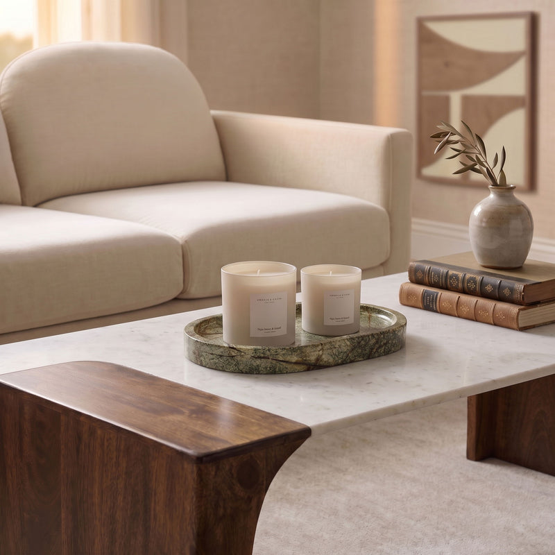 Dark green marble tray holding two white candles on a table.