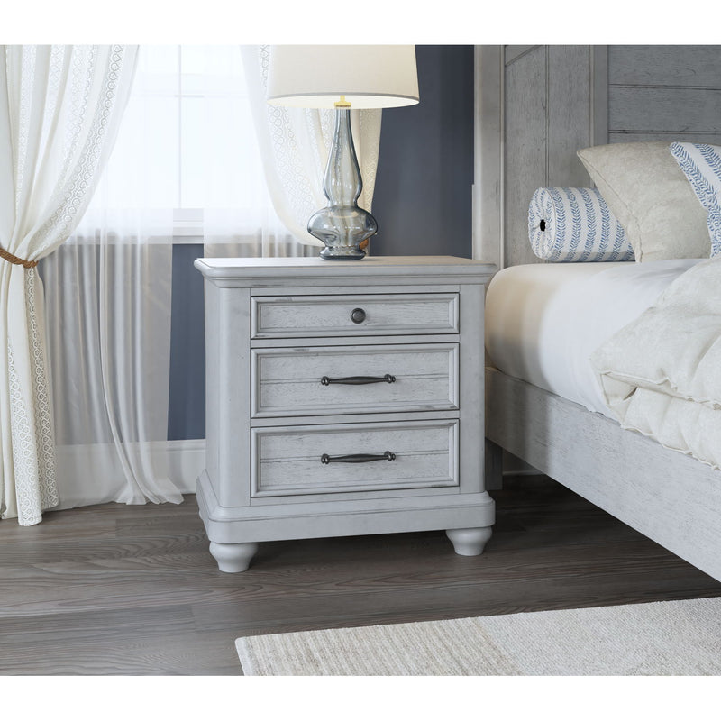 Gray wood 3-drawer nightstand with metal pulls and turned legs beside bed.