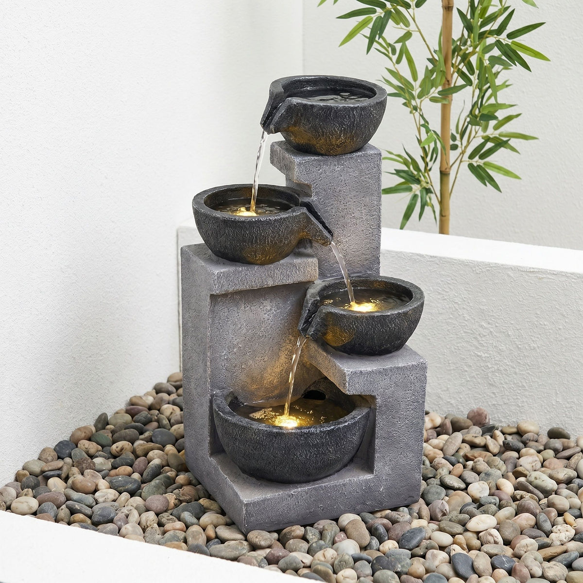 Gray four-tier fountain with cascading water and warm LED lights in the bowls.
