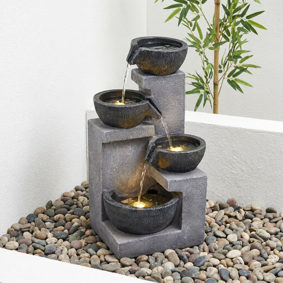 Gray four-tier fountain with cascading water and warm LED lights in the bowls.