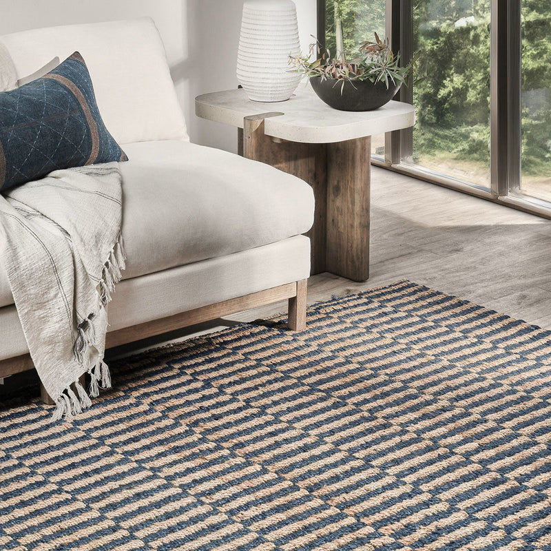 Blue and natural jute rug with striped pattern shown under a living room chair