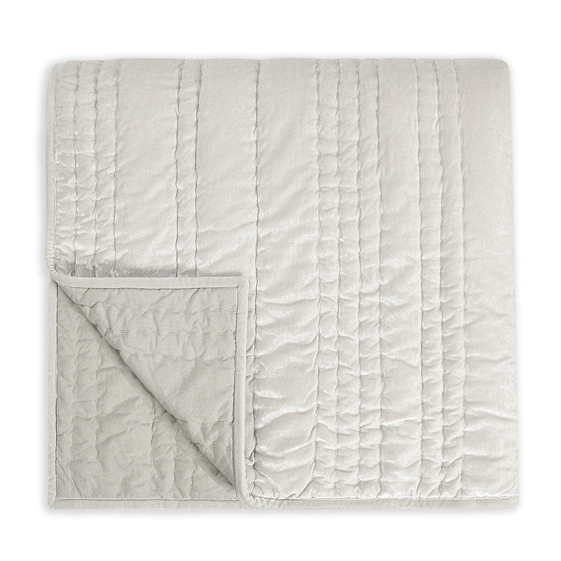 Folded ivory quilt with quilted texture and vertical channel stitching