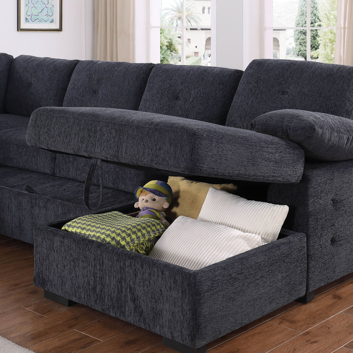 Dark gray sectional with open storage ottoman holding pillows and toys