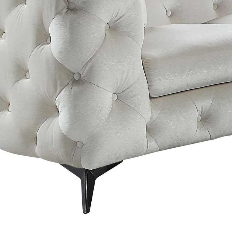 Beige tufted sofa arm and back with button tufting and matching pillow