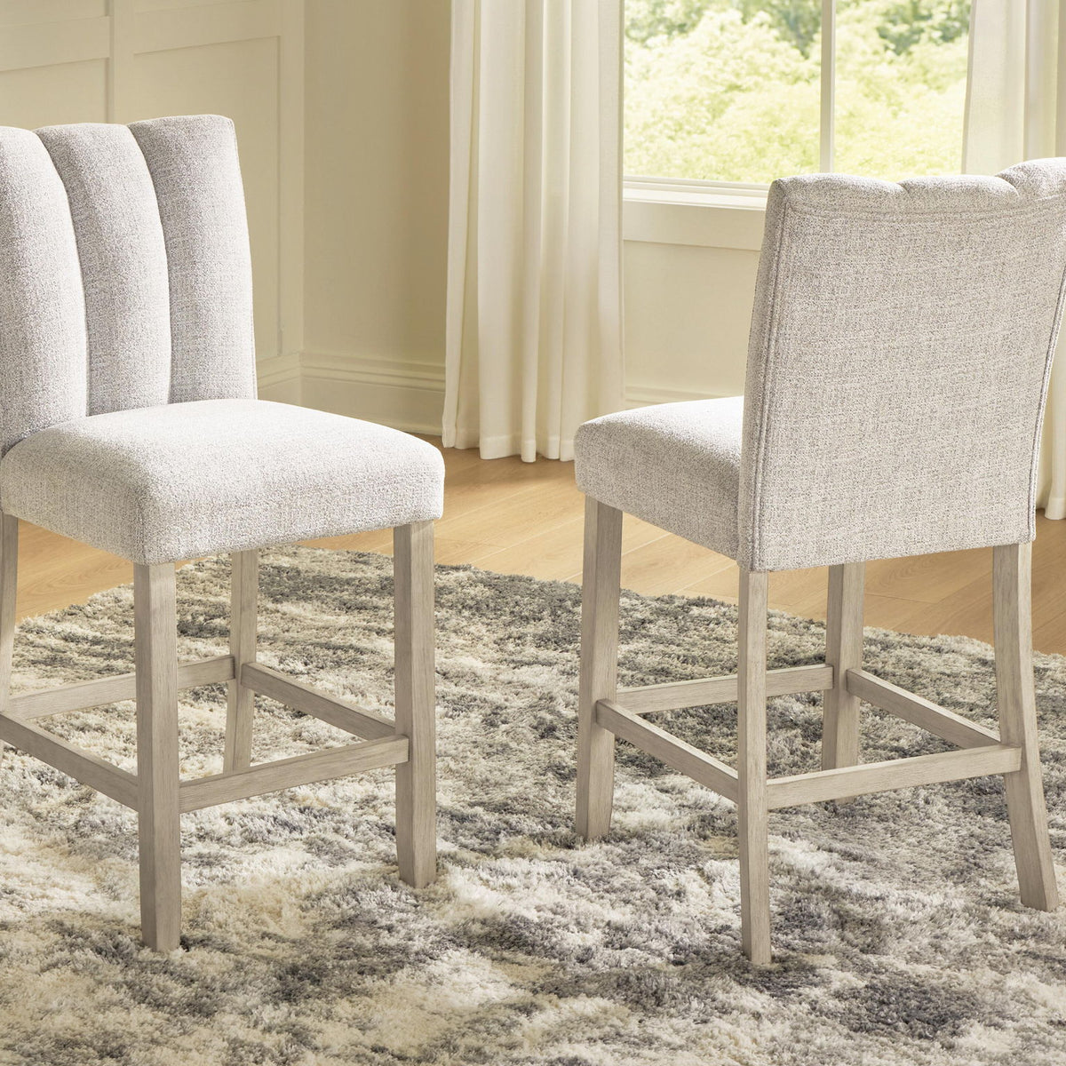 Two upholstered barstools with tall backs, light beige fabric and wooden legs