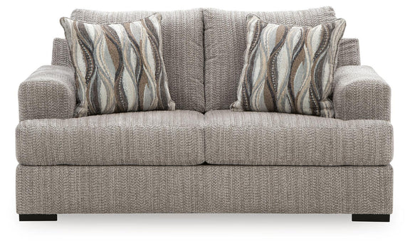 Gray textured loveseat with armrests, two seat cushions, and striped wave throw pillows