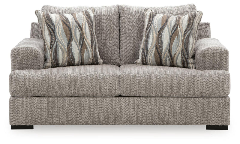 Gray textured loveseat with armrests, two seat cushions, and striped wave throw pillows