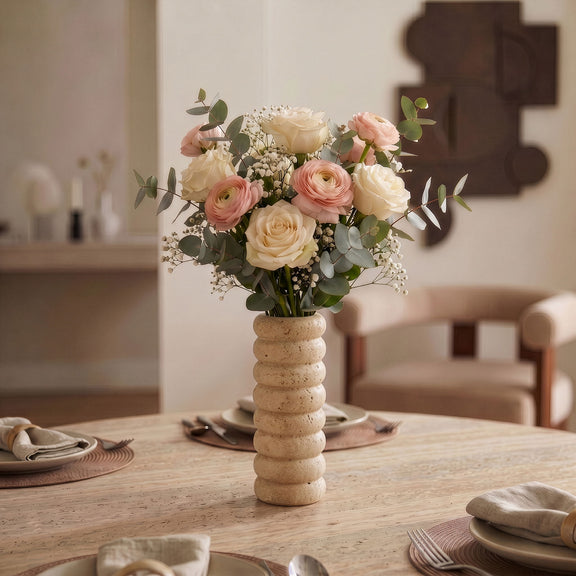 Beige travertine vase holding a mixed bouquet of roses