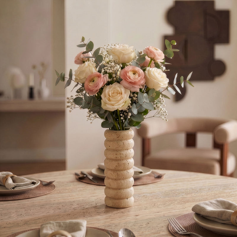 Beige travertine vase holding a mixed bouquet of roses