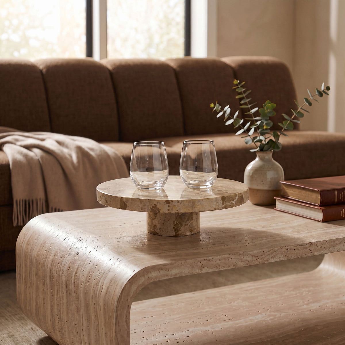Beige marble pedestal serving tray with round top, styled on a wooden table