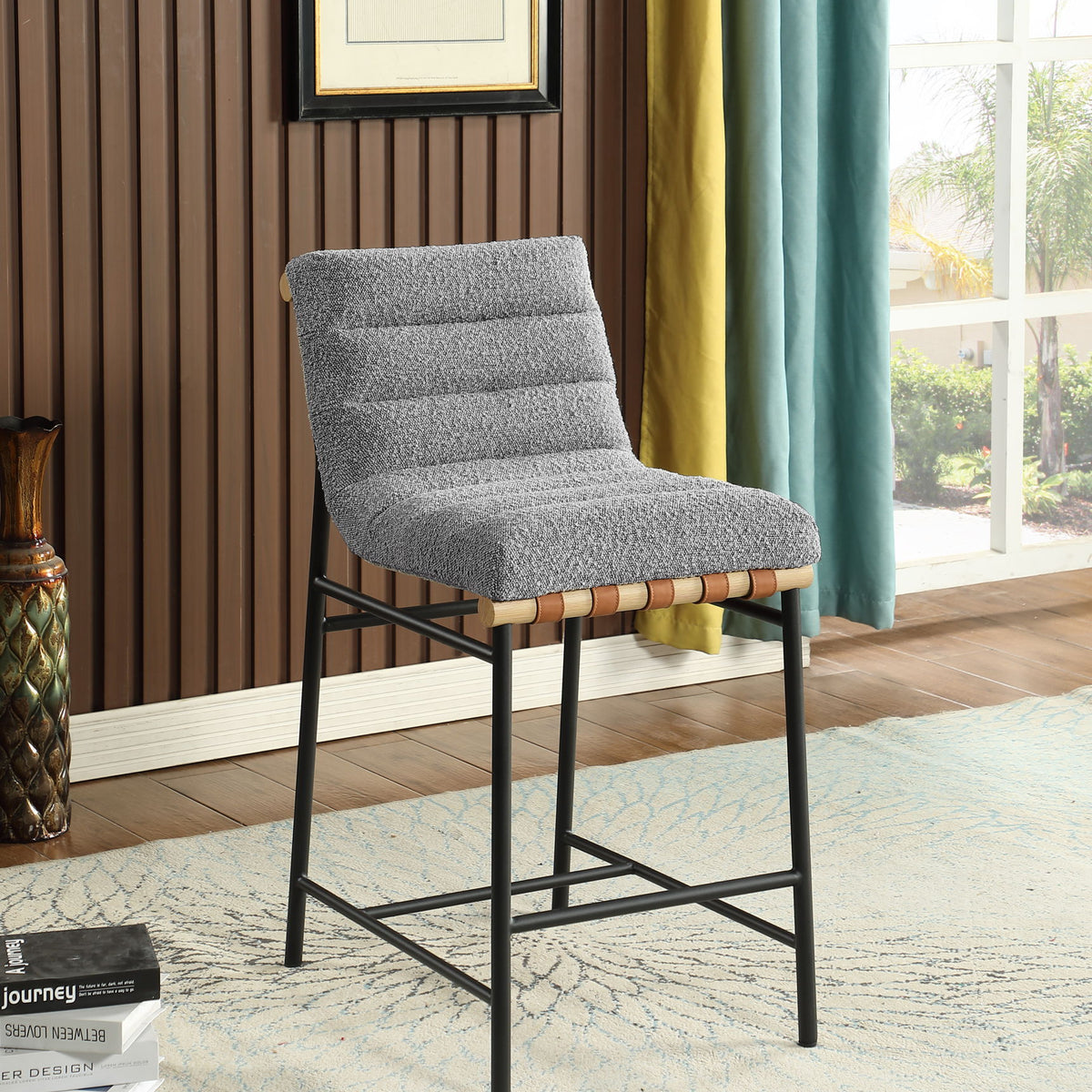 Gray boucle counter height bar chair with padded back, black legs, and wood accent rail