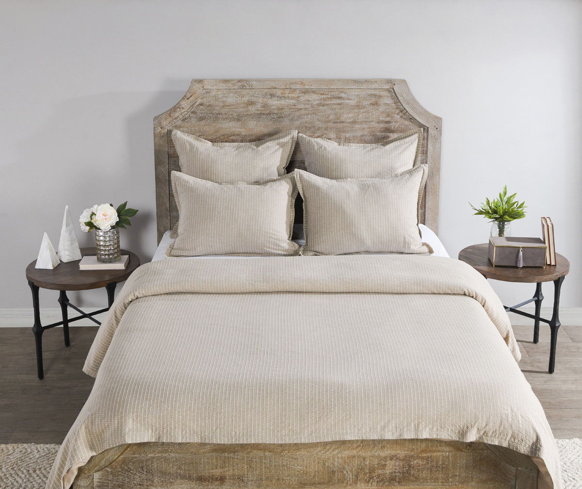 Beige duvet and pillows on bed with tufted throw accents