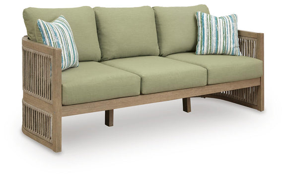 Outdoor sofa with sage green seat and back cushions, striped pillows, light wood slatted arms