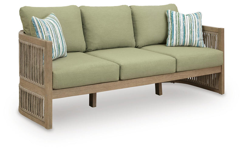 Outdoor sofa with sage green seat and back cushions, striped pillows, light wood slatted arms