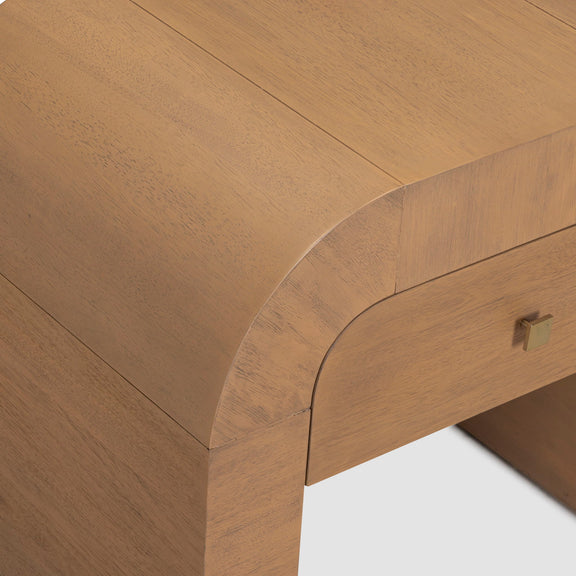 Light brown wood nightstand corner with drawer edge and metal handle