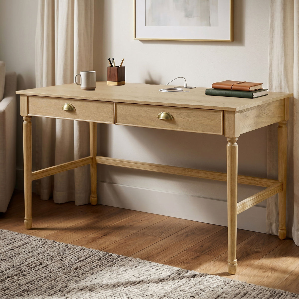 Light brown writing desk with two drawers, brass-tone pulls, and lower shelf