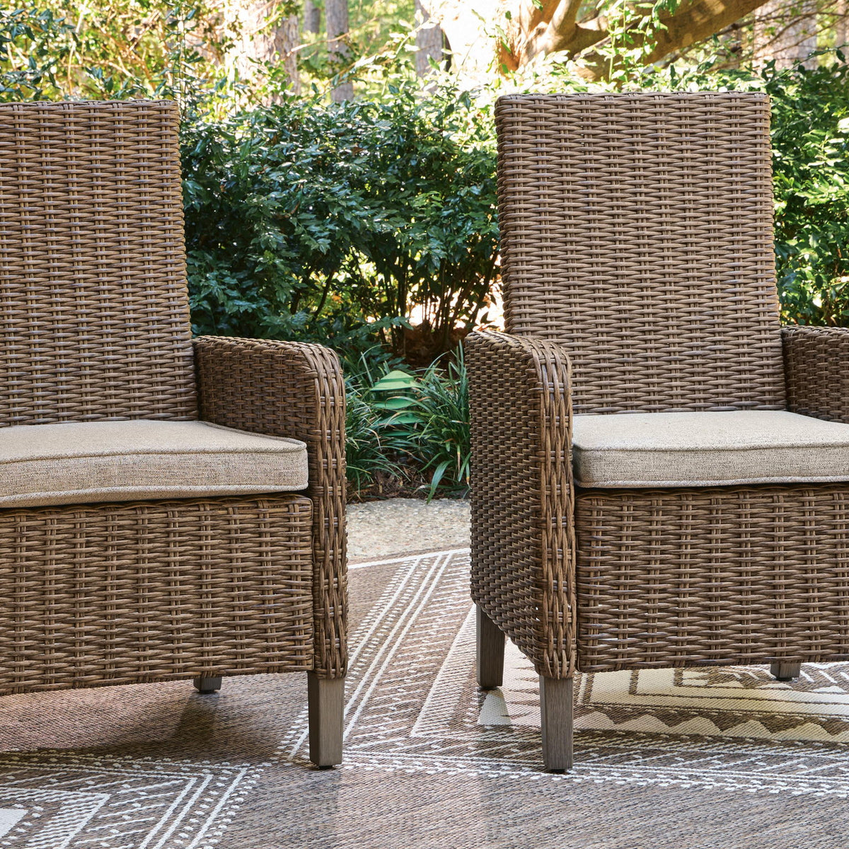 Outdoor set of 2 beige woven arm chairs with light seat cushions and arms