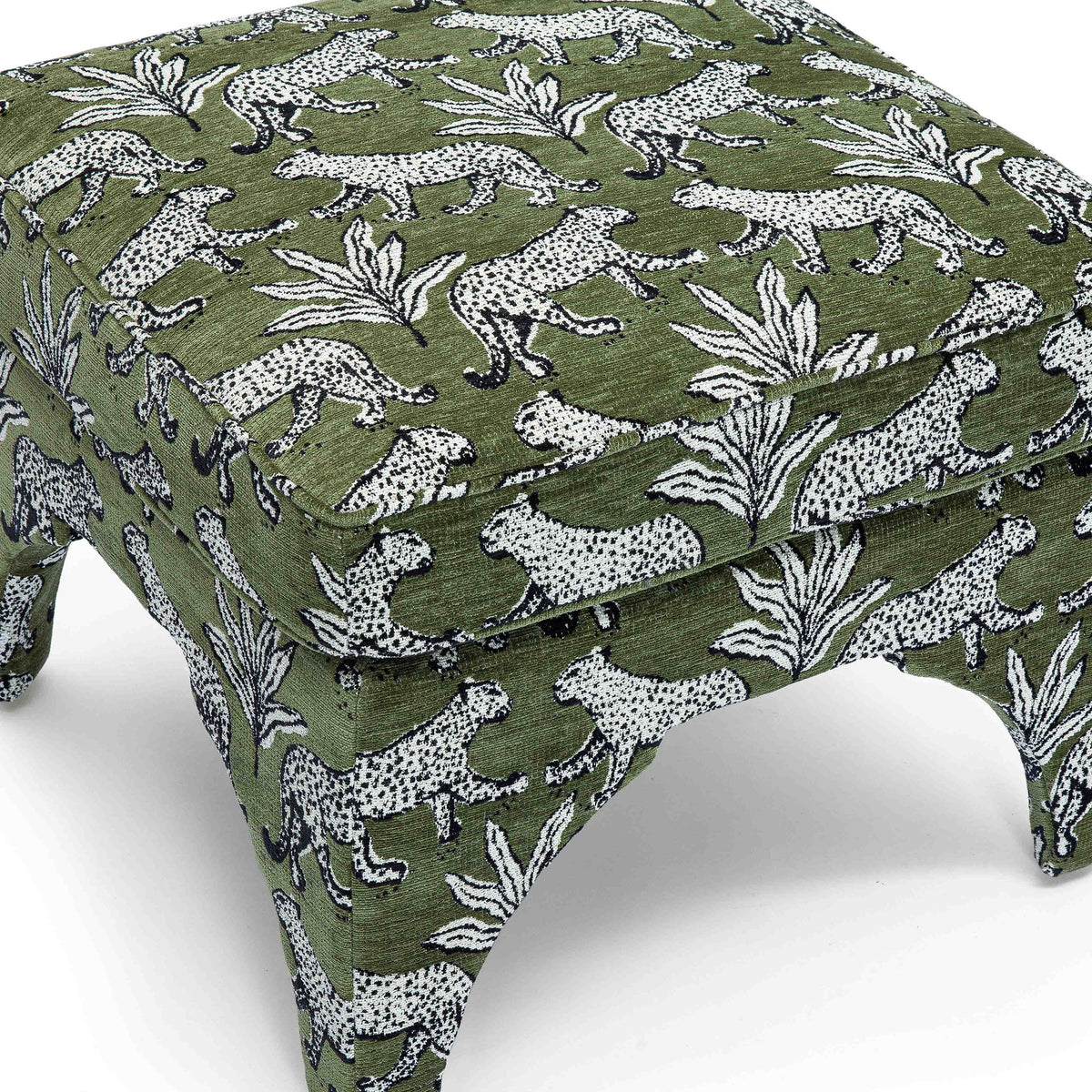 Upholstered ottoman detail: dark green fabric with white jungle animals and leaves, padded top