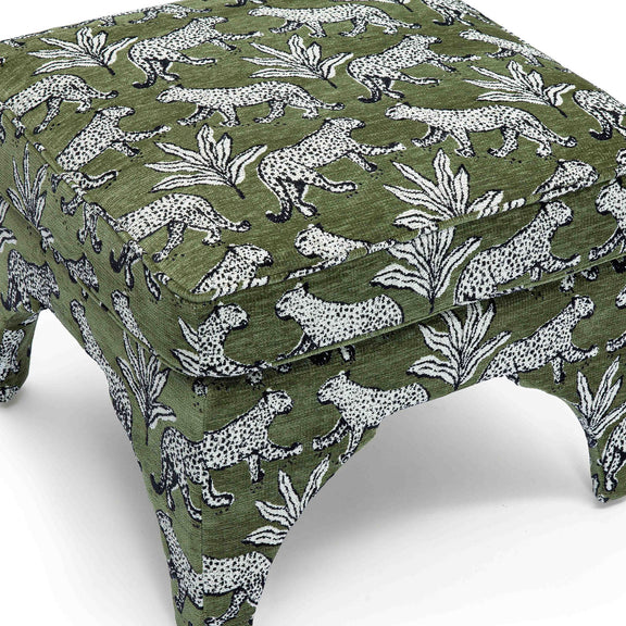 Upholstered ottoman detail: dark green fabric with white jungle animals and leaves, padded top