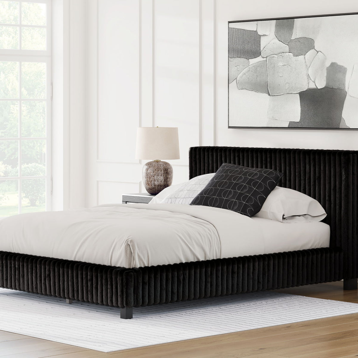 Black upholstered bed frame with tall ribbed headboard and white comforter and pillows.