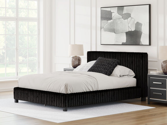 Black upholstered bed frame with tall ribbed headboard and white comforter and pillows.