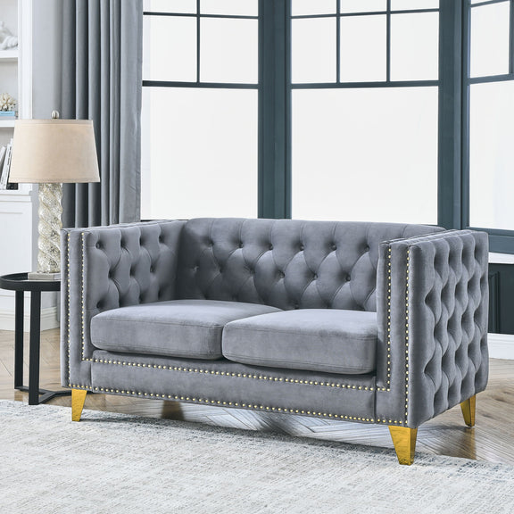 Dark gray button-tufted sofa with nailhead trim, two cushioned seats, and gold legs