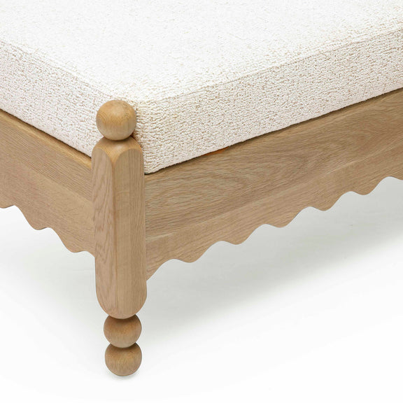 Close-up of cream cushion on light wood leg with round knob feet.