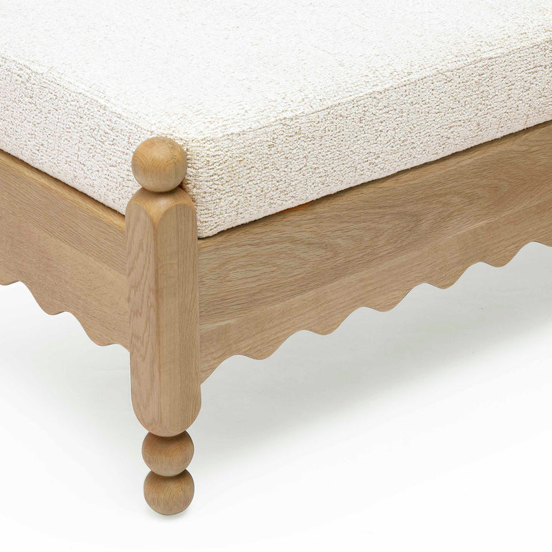 Close-up of cream cushion on light wood leg with round knob feet.