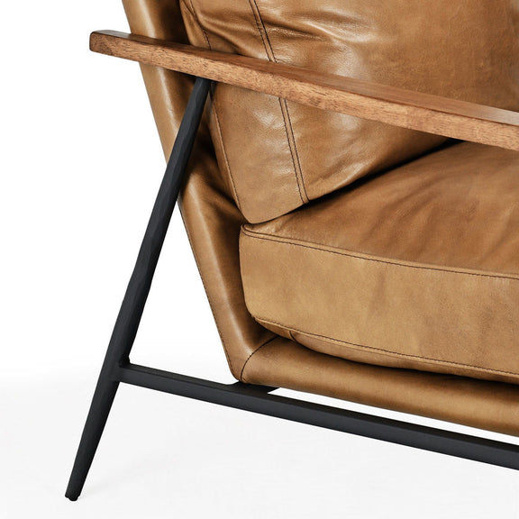 Close-up tan leather club chair arm and seat with visible stitching seams