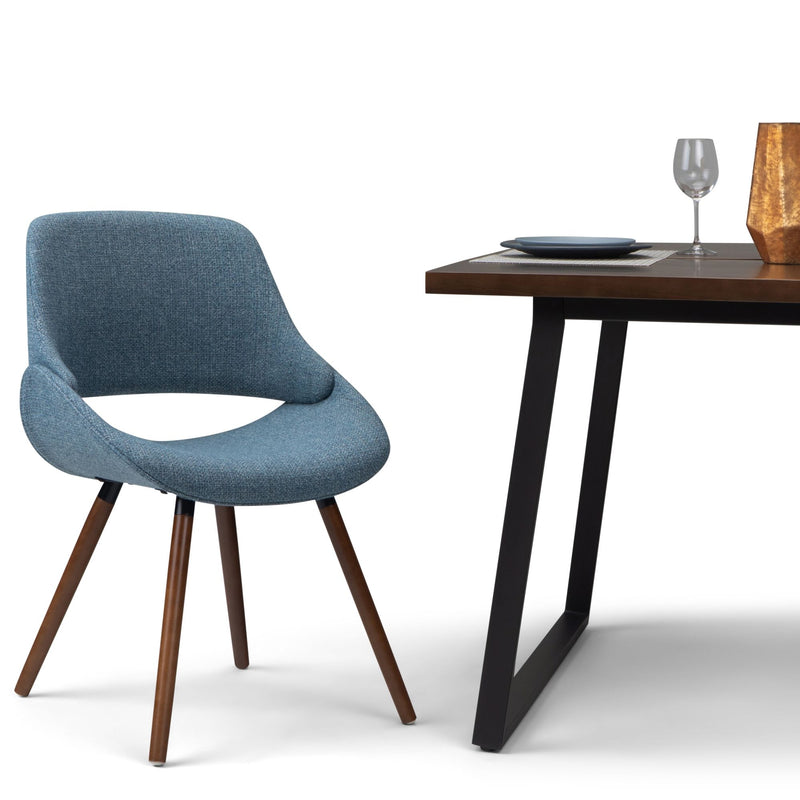 Blue upholstered dining chair with wood back and tapered legs, side view