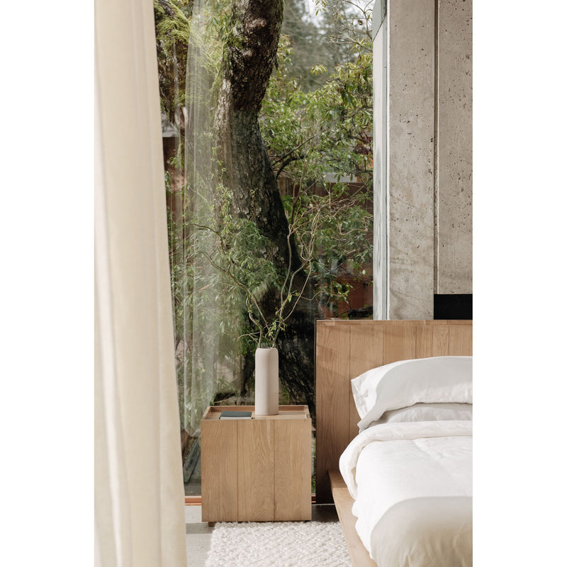 Natural oak king bed with slatted headboard, white bedding and wood nightstand