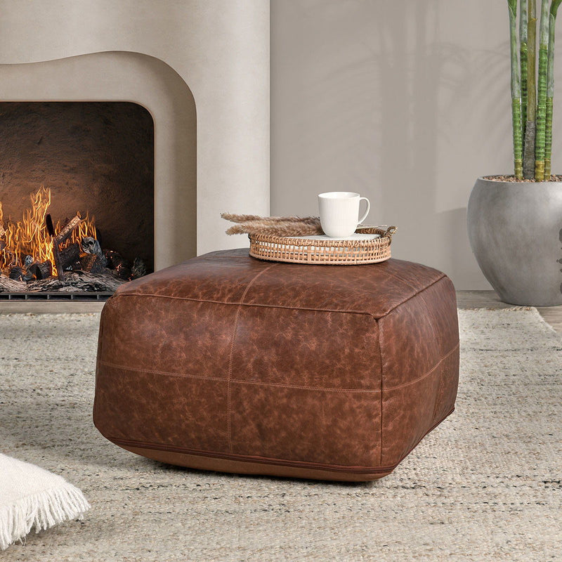 Chestnut leather pouf with stitched panels and rounded square silhouette.
